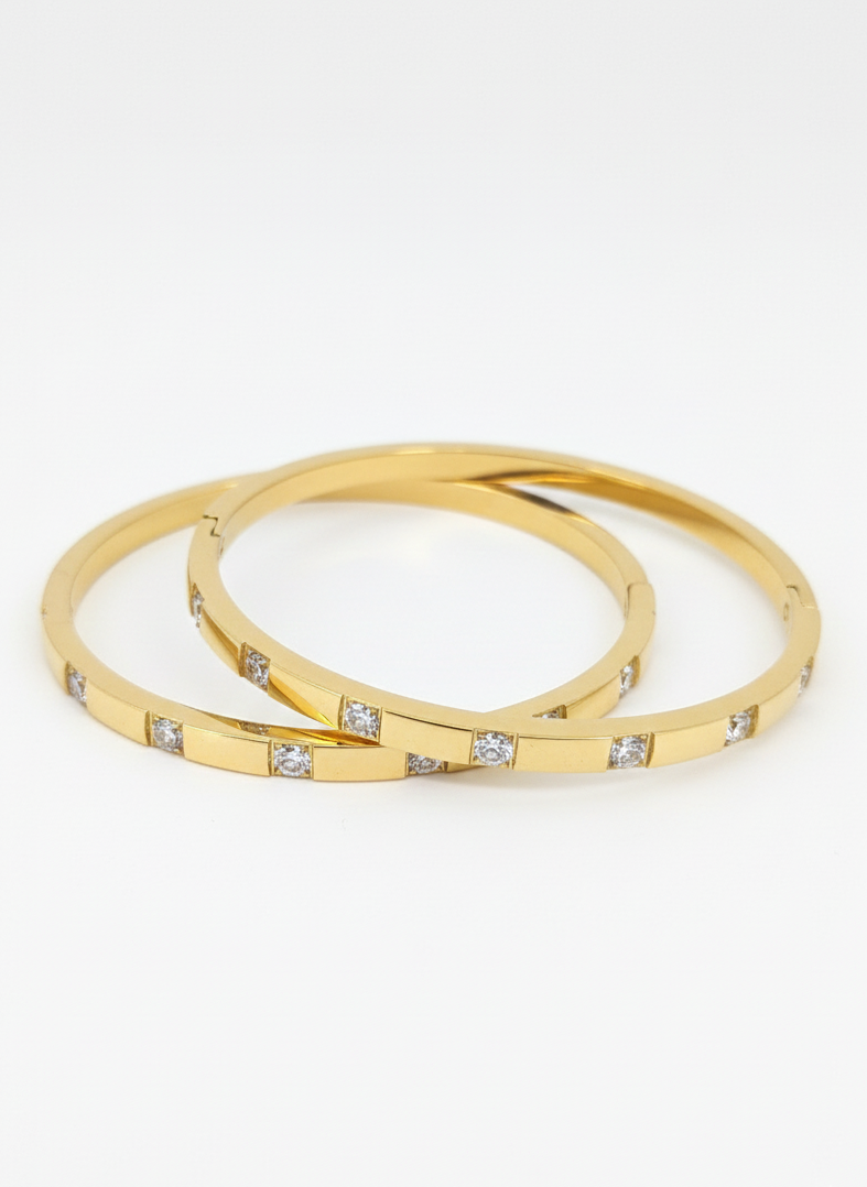 Two gold bangles with embedded diamonds on a white background