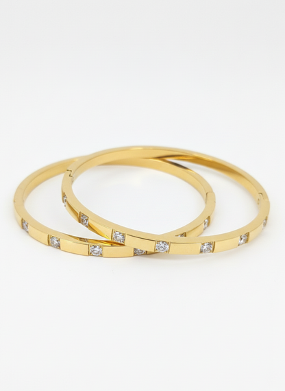 Two gold bangles with embedded diamonds on a white background